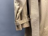 le dos d'un trench-coat beige orné d'une boucle dorée