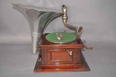 un gramophone argenté posé sur un socle en bois, orné d'une plaque verte