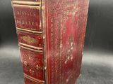 an old red book sitting on top of a black table