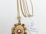 a gold necklace with a red and white stone in the center