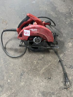 une scie circulaire rouge posée sur le sol en béton