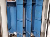 several blue lockers in a run down room with broken doors