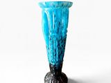 a blue glass vase with a black base on a white background