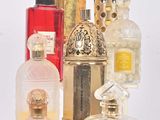 de nombreux flacons de parfum posés sur une étagère blanche