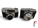 two cameras sitting next to each other on a white surface
