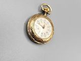 une image représentant une petite montre de poche en or posée sur une surface blanche