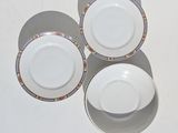 three white plates with colorful designs on them sitting on a table