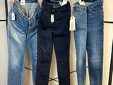 trois paires de jeans suspendues à un portant dans un magasin de vêtements
