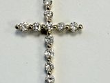 un gros plan d'un pendentif en forme de croix en diamant posé sur une surface blanche