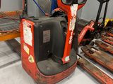 a red forklift in a warehouse with pallets on the floor
