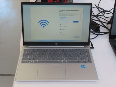 a laptop computer sitting on a desk with a wifi sign on the screen