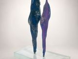 sculpture of two people standing on a glass platform with a white background