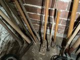 a lot of shovels that are leaning against a brick wall