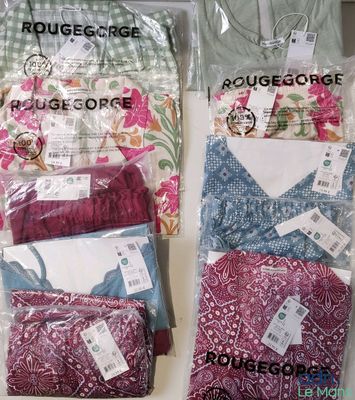 Trois sacs de vêtements sont posés sur une table, avec leurs étiquettes encore attachées.