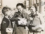 three children standing next to each other and one is holding a piece of paper