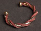 a close up of a red and gold bracelet on a black surface