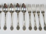 six forks and six spoons on a white table