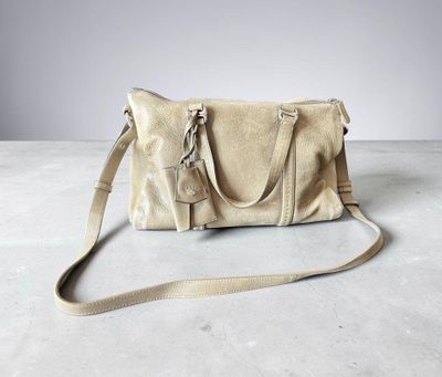 un sac à main en cuir beige posé sur un sol en béton