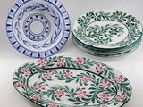 three plates with floral designs on them sitting on a white surface