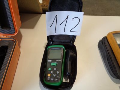 a green and black meter sitting on a table next to other items