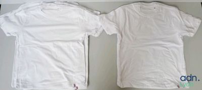 two white t - shirts sitting on top of a table next to each other