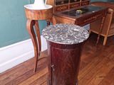 une petite table au plateau en marbre, à côté d'une autre petite table sur laquelle se trouve un vase
