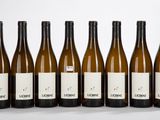 six bouteilles de vin sont alignées sur une surface blanche