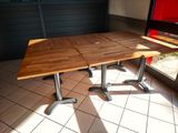 a wooden table with two metal legs on a tiled floor