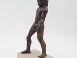 a bronze statue of a man holding a ball on a marble base