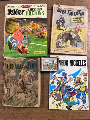 Plusieurs bandes dessinées sont posées sur une table au plateau en bois.
