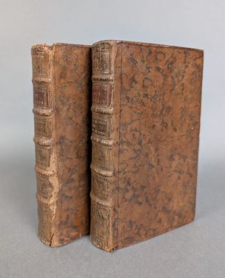two old books sitting on top of each other on a table