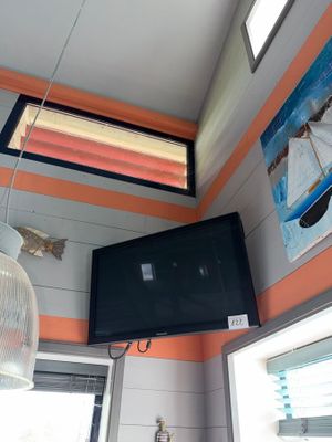 a flat screen tv hanging from the ceiling in a small room
