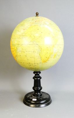 un globe jaune posé sur un socle noir, lui-même posé sur une surface blanche