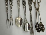 five spoons and a pair of scissors sitting on a table