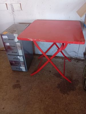 a small red table with a red folding chair next to it