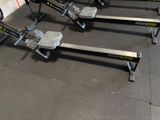 row of rowing machines lined up in a row in a gym