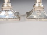 pair of silver candlesticks with ornate designs on each of them