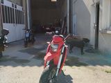 a red motorcycle parked in front of a garage