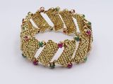 a close up of a gold bracelet with multi colored stones
