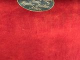an old suitcase with a label on it sitting on a red carpet