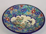 un bol bleu orné d'un motif représentant un oiseau et des fleurs