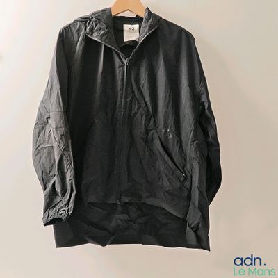 une veste noire suspendue à un cintre accroché au mur