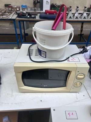 a microwave sitting on top of a table with a bucket of food in it