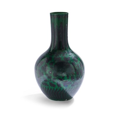 un vase vert posé sur une surface blanche