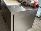 un plan de travail en acier inoxydable dans une cuisine professionnelle, sur lequel sont disposés de nombreux condiments