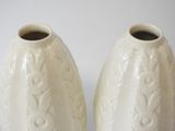 two white vases sitting next to each other on a table
