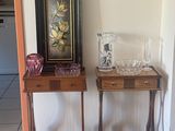 two small tables with vases on them in a room