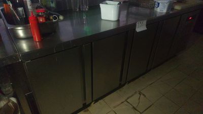 stainless steel counter top in a kitchen with a lot of bottles and cups on it