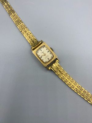 une image représentant une montre en or avec un cadran blanc sur un fond argenté