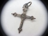 a silver cross on a white surface with a black background